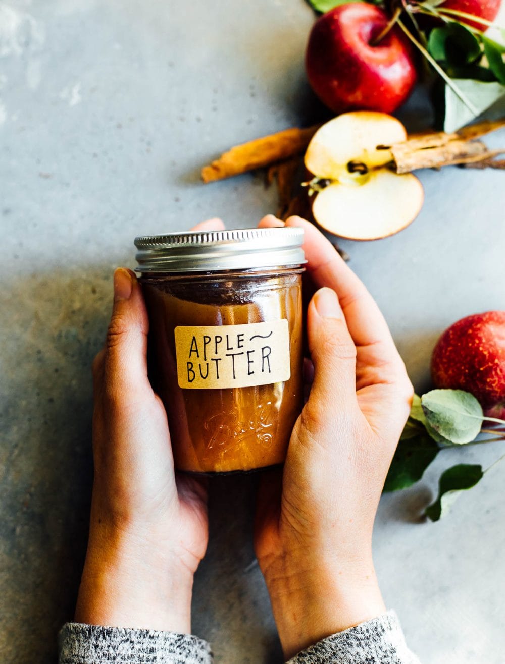 woman holding apple butter in hands, with a brown craft label