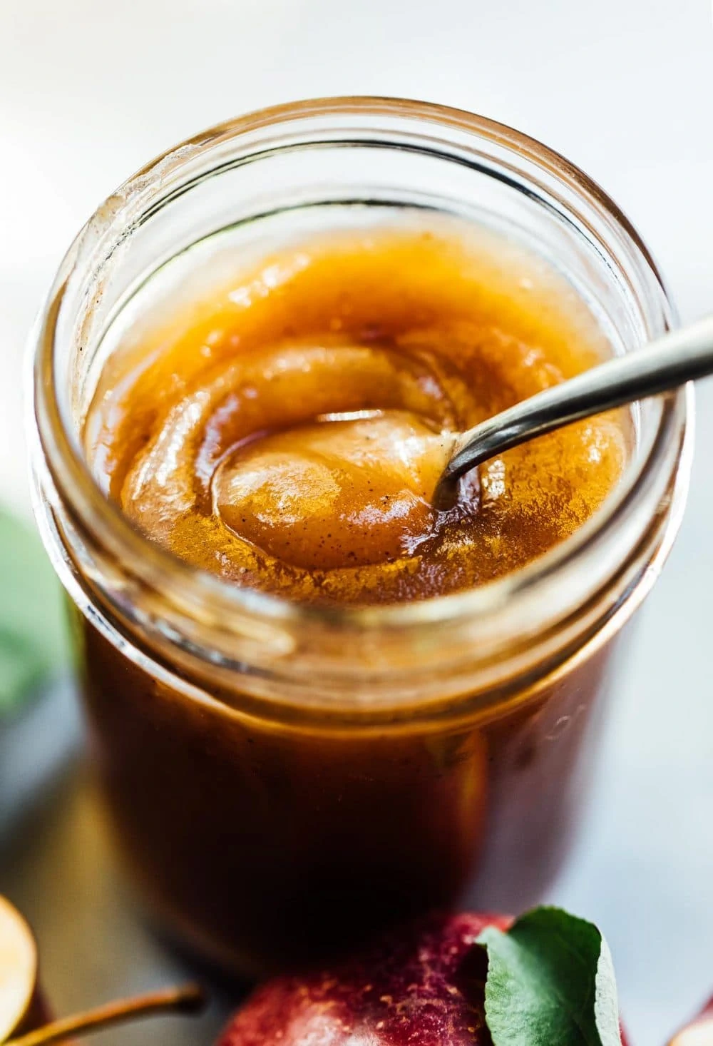 apple butter in a glass jar, top off, with spoon in it. 