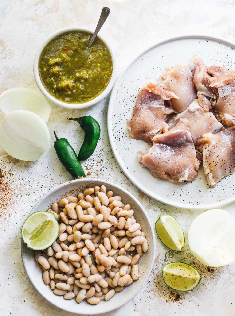 ingredients for green chili chicken soup, white beans, chicken thighs, salsa verde, onion, jalapenos