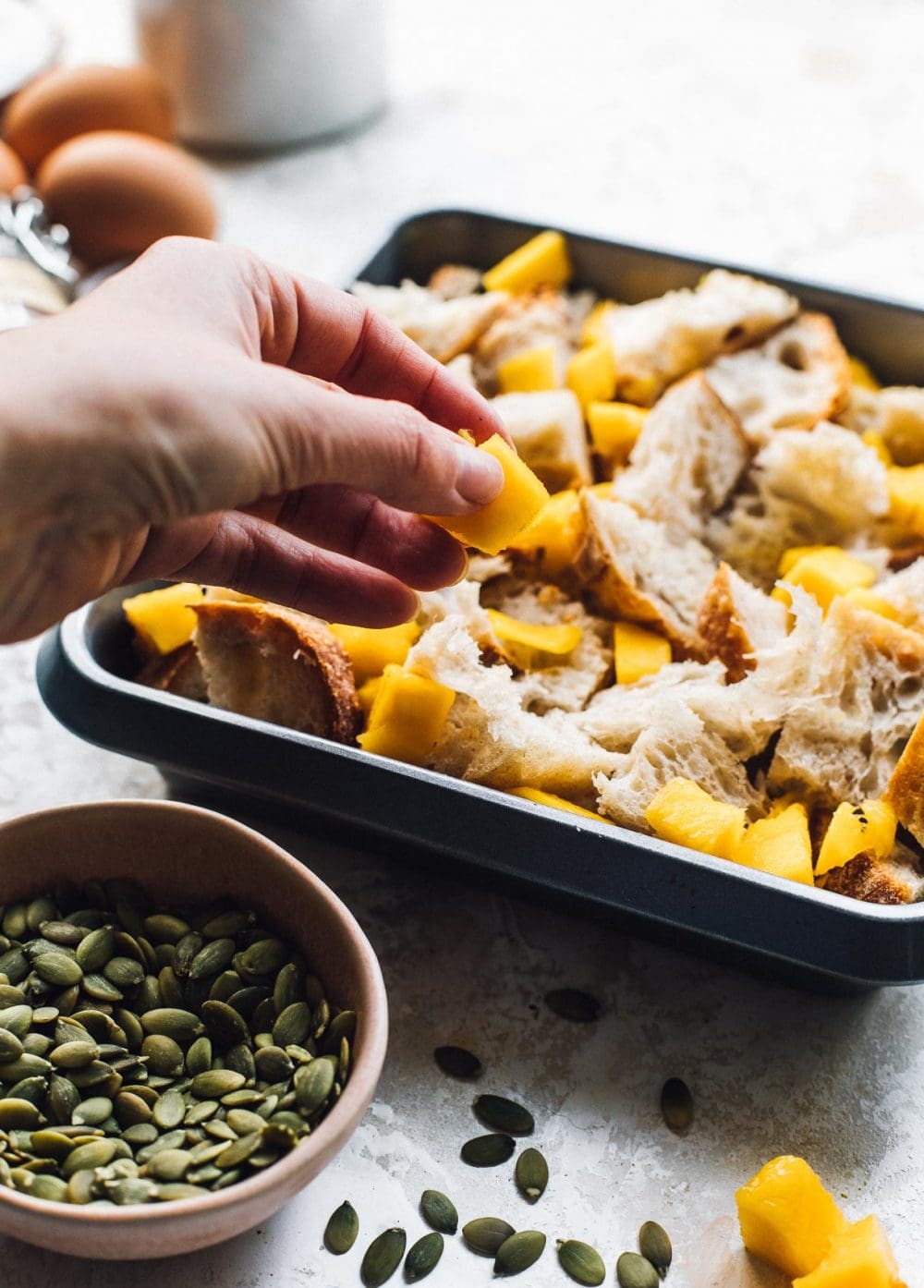 adding a piece of mango to the top of bread pudding that is in a square pan.