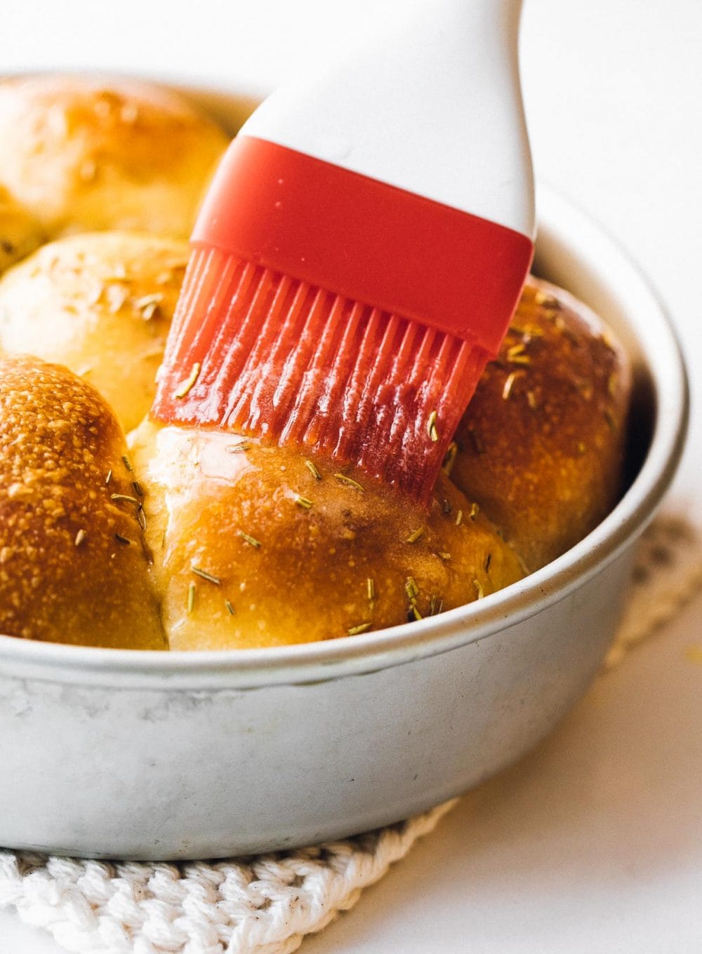 brushing butter on sourdough dinner rolls