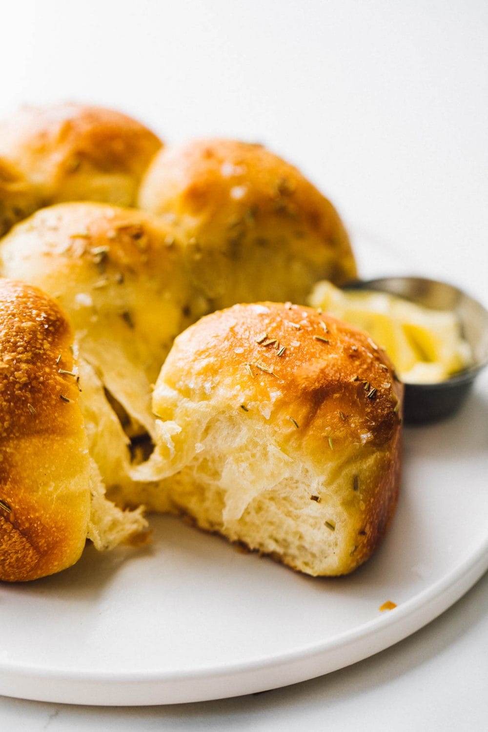 soft sourdough dinner rolls on a white plate