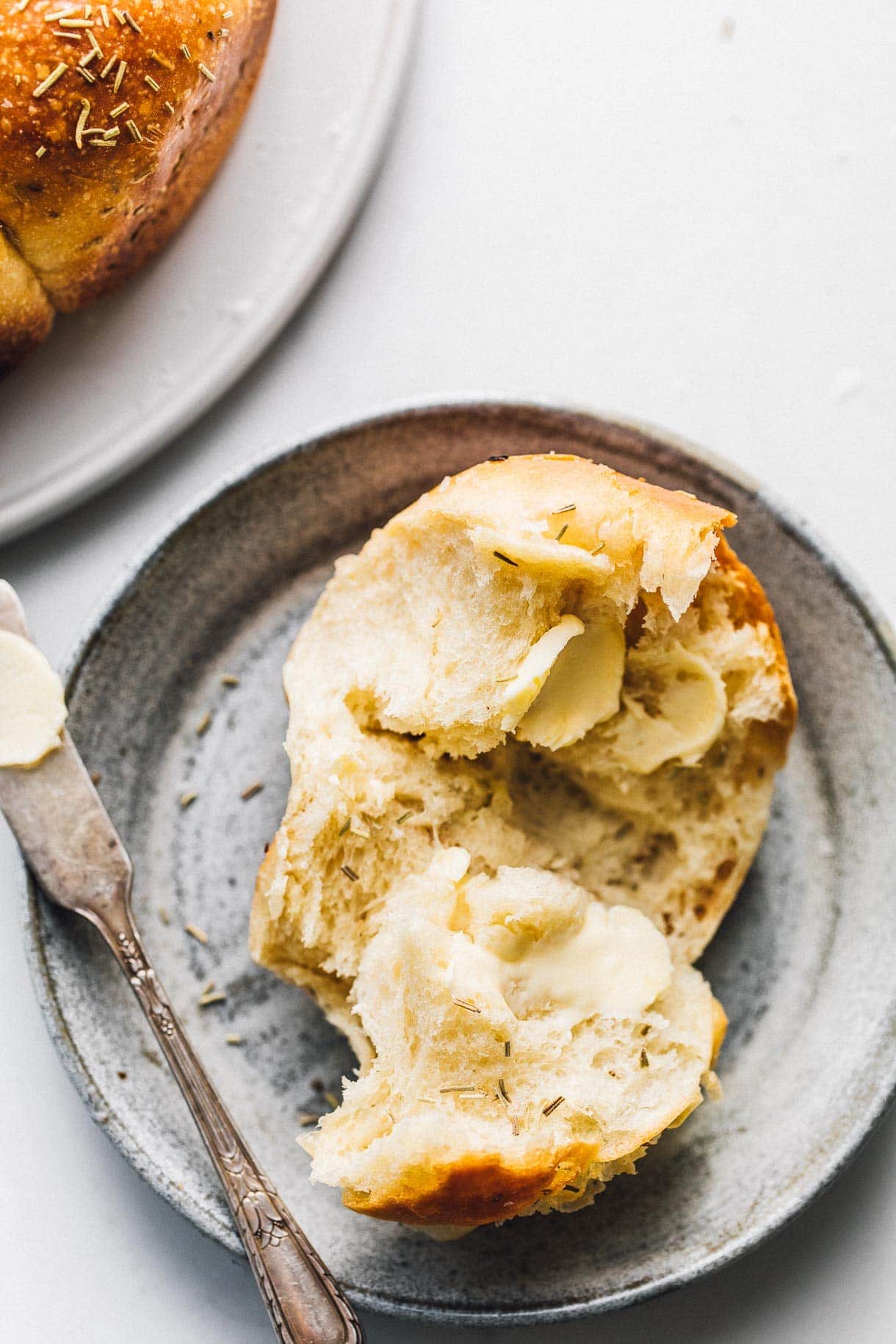 sourdough dinner roll cut in half with buttered knife