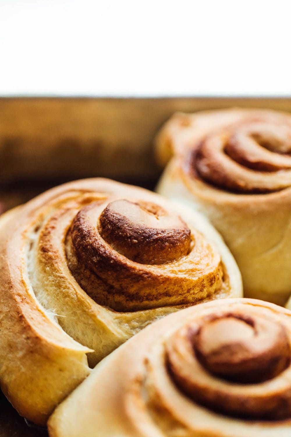 close up photo of sourdough sticky buns right after they've finished baking, still in pan. 