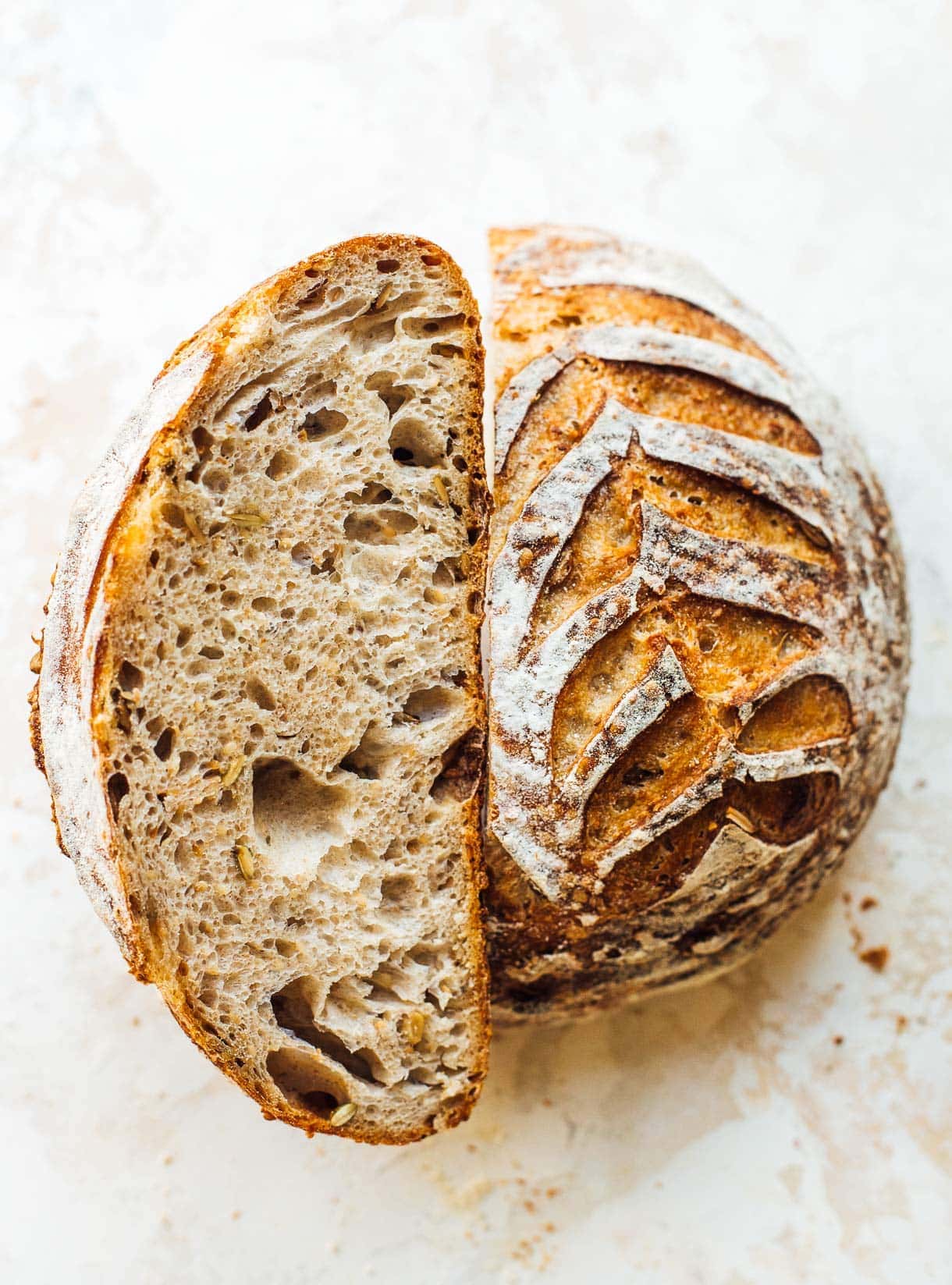 seeded sourdough loaf cut in half, with one half crumb side up.