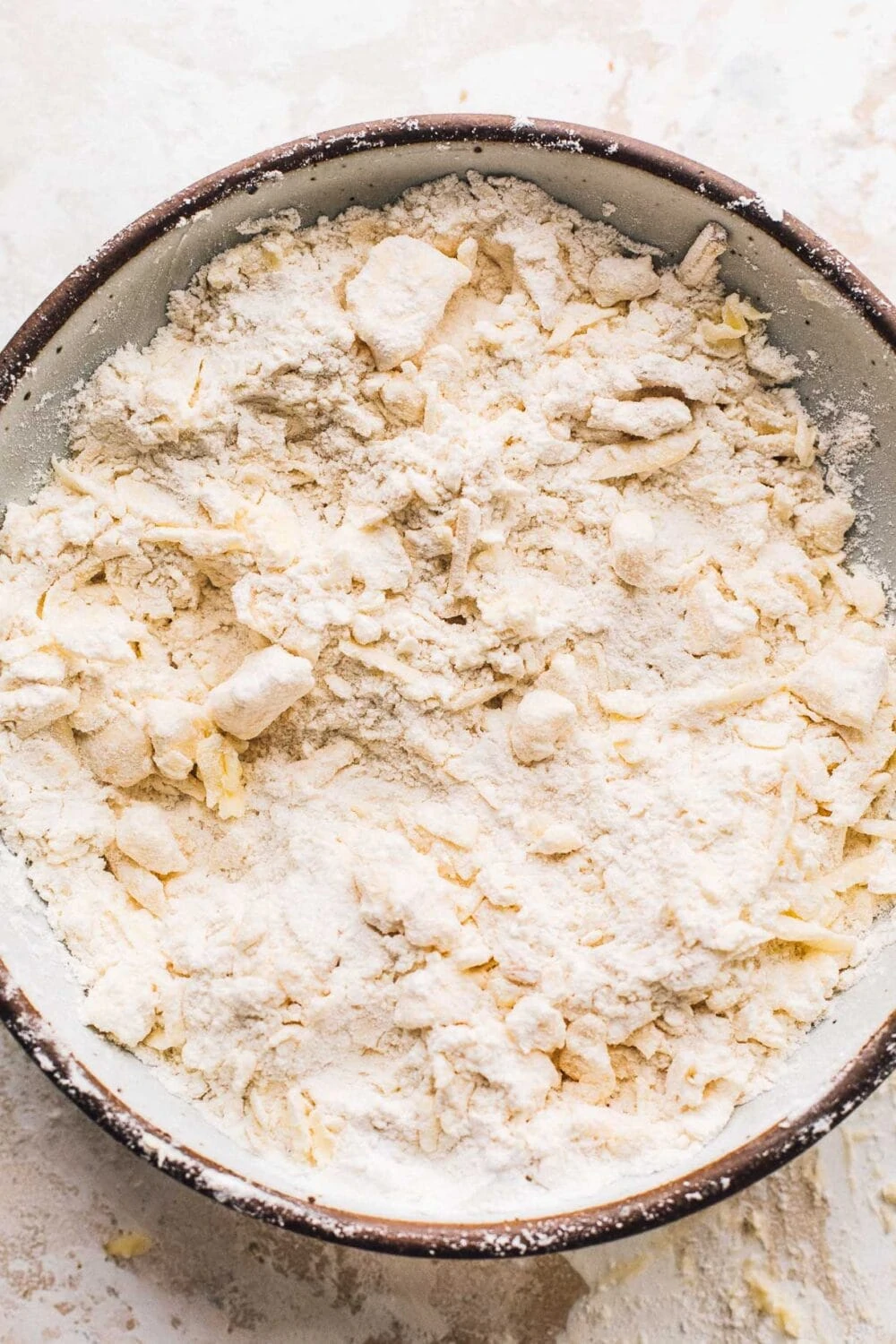 bowl of flour, grated butter, grated cheese in prep for making biscuits.