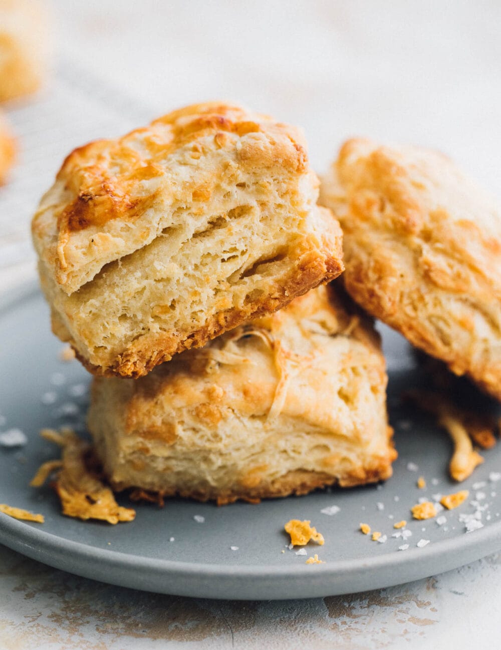 Two biscuits stacked on a blue plate, with one biscuit leaning up against the stack of two.