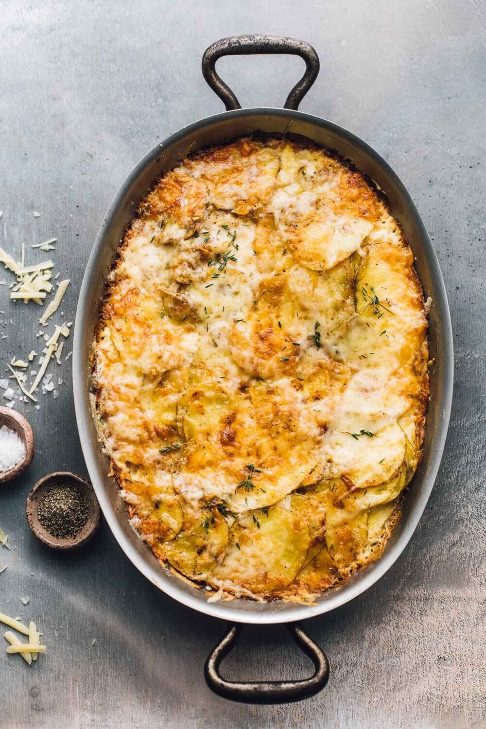 pan of au gratin potatoes with small bowl of salt and pepper to the left.