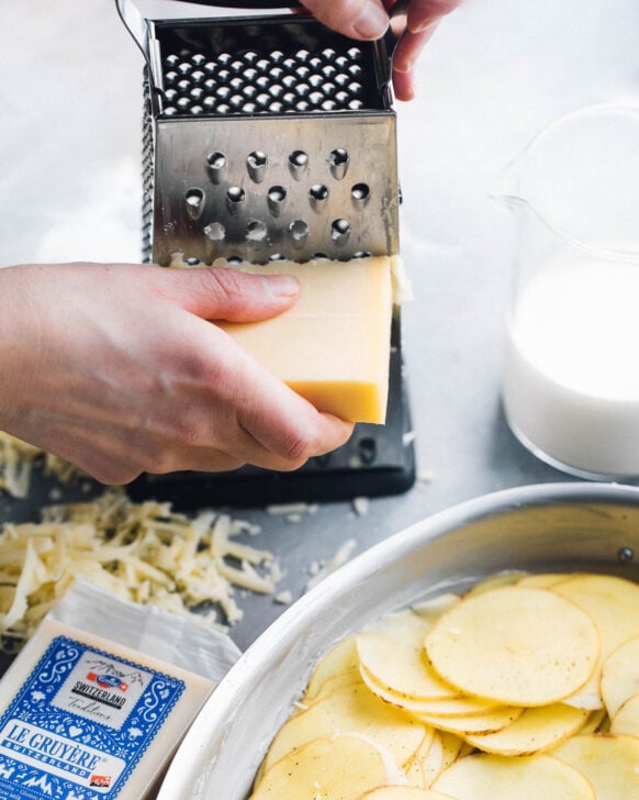 grating gruyere cheese on a box grater
