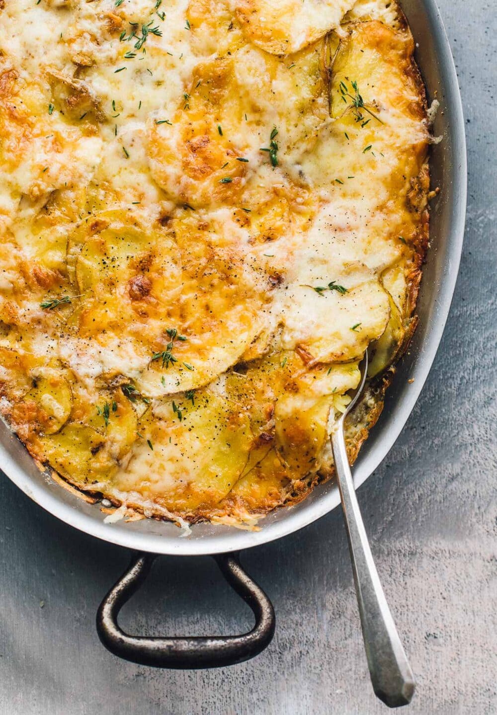 au gratin potatoes in an oval dish with a spoon on the right side of the dish