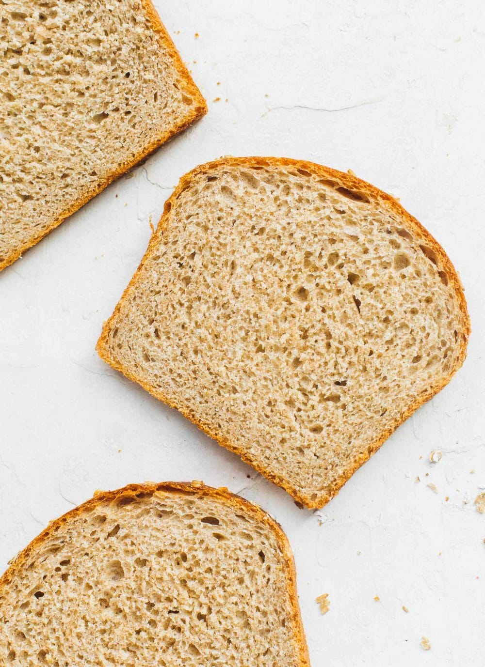 whole wheat sourdough sandwich bread slices laying on white backround