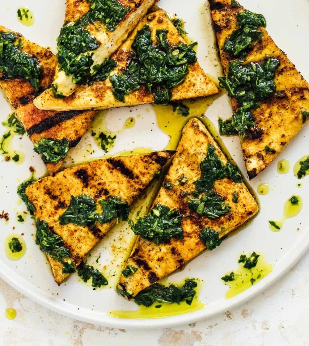 grilled tofu with green sauce on a white plate 