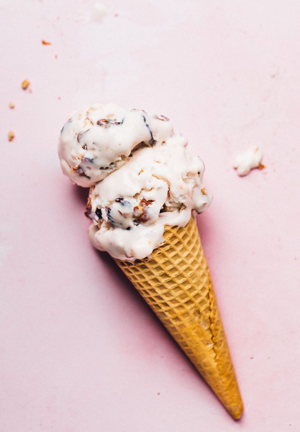 tart cherry ice cream in a cone, on pink background.