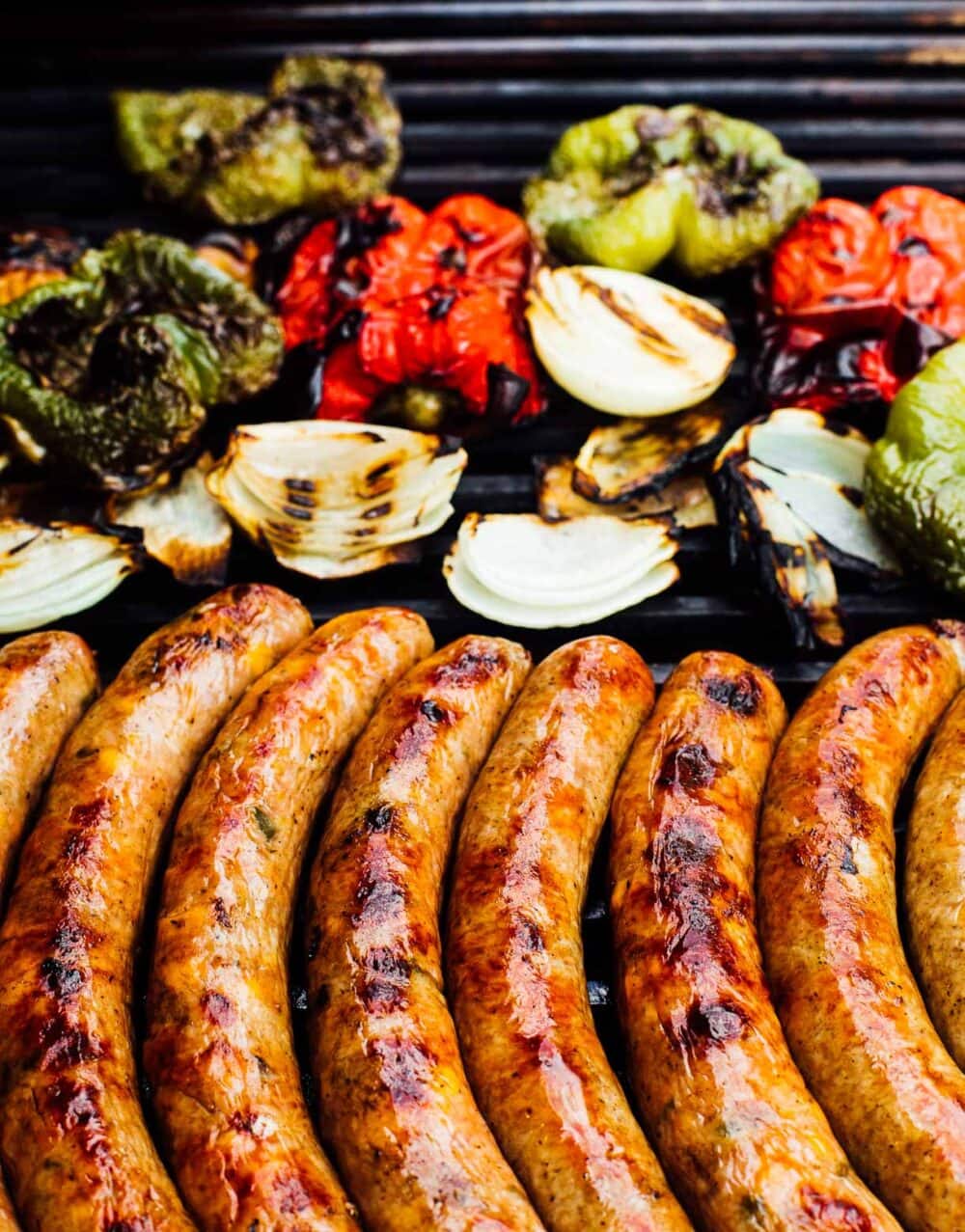 brats and peppers, onions, on a grill