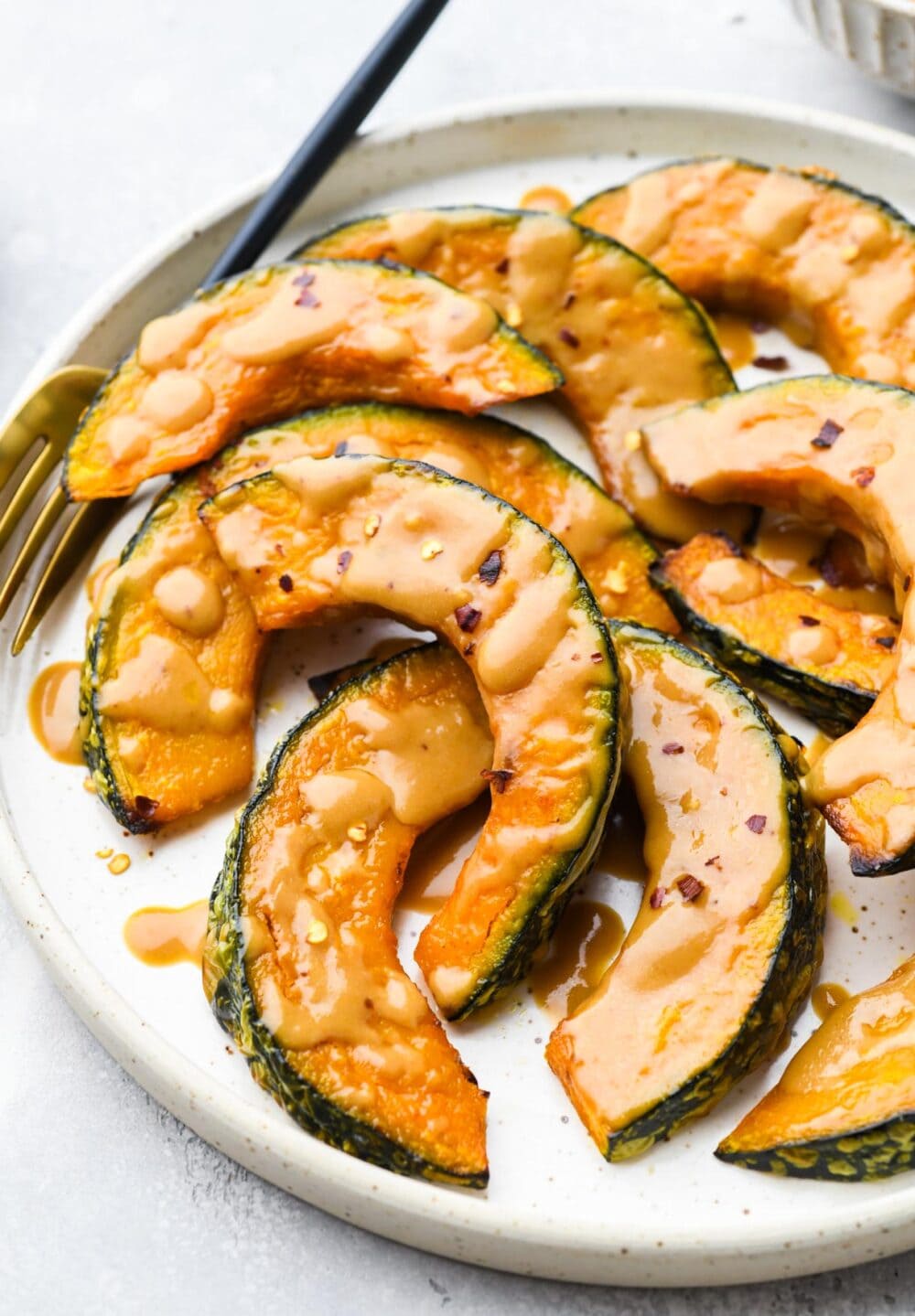 roasted kabocha squash wedges with miso glaze on a white plate with gold fork