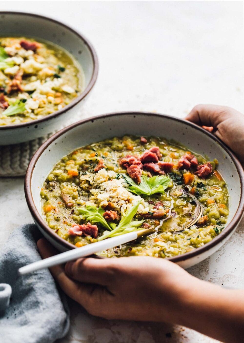 split pea soup with ham in a white bowl with gold spoon