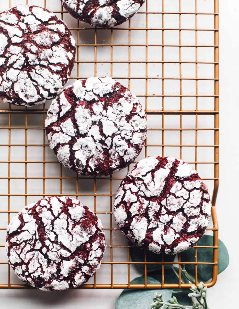 red velvet crinkle cookies on a copper cooling rack