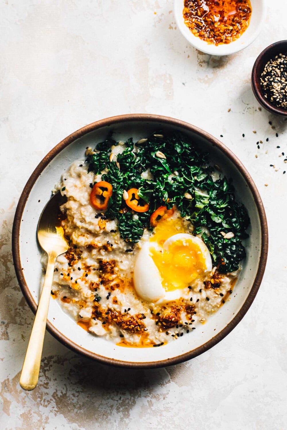 savory oatmeal in a bowl with gold spoon, egg and greens in the bowl. 