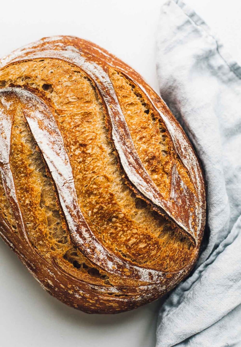 loaf of spelt sourdough bread with blue linen. 