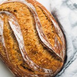 loaf of spelt sourdough bread with blue linen.