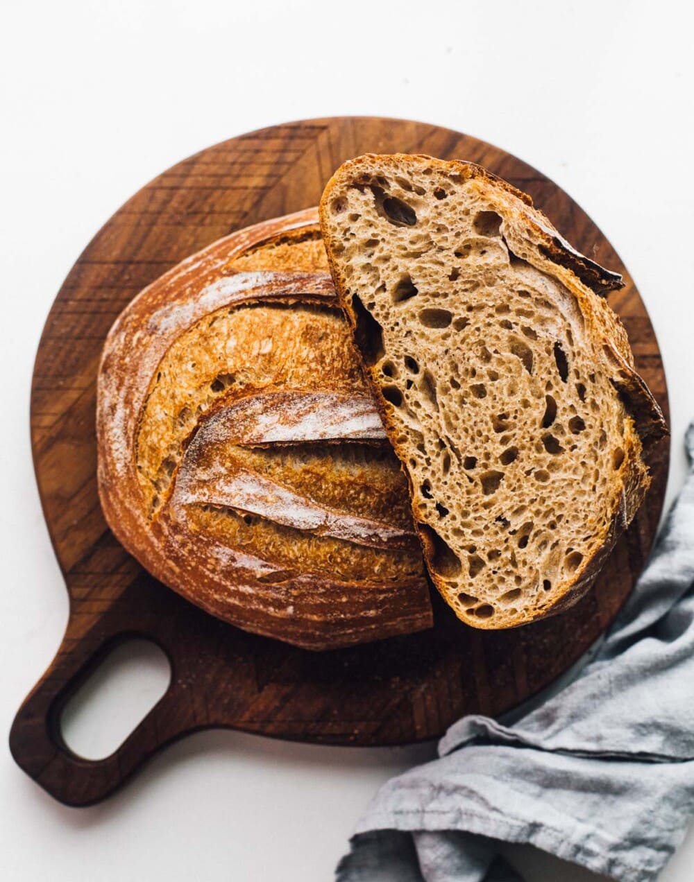 spelt sourdough bread on a cutting board, cut in half.