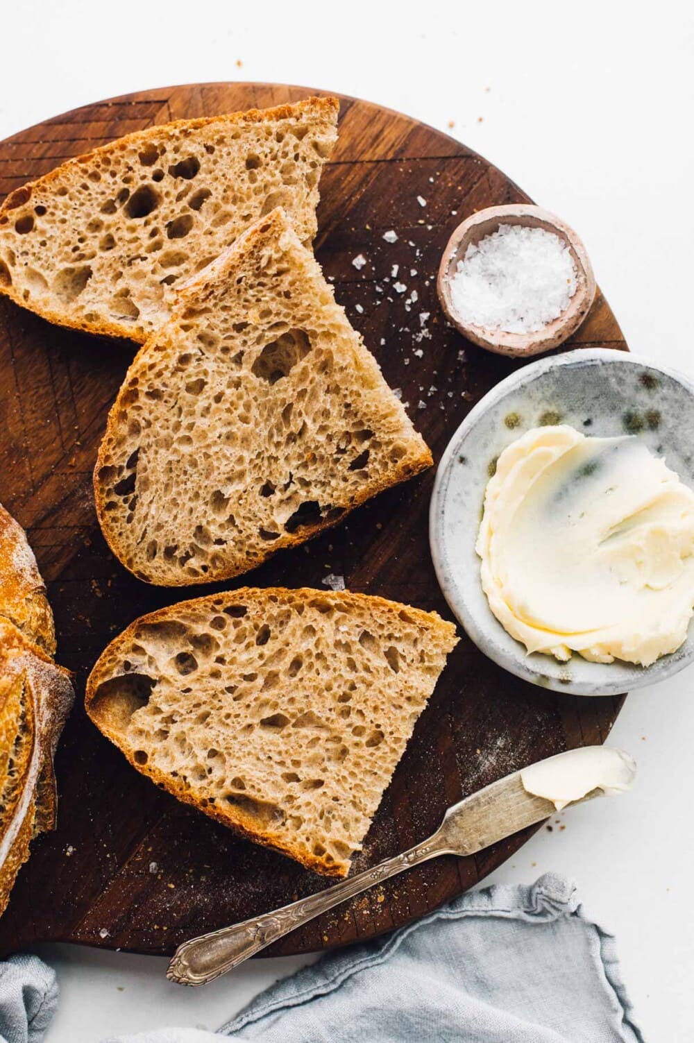 sliced spelt sourdough bread on a cutting board, with butter and knife.