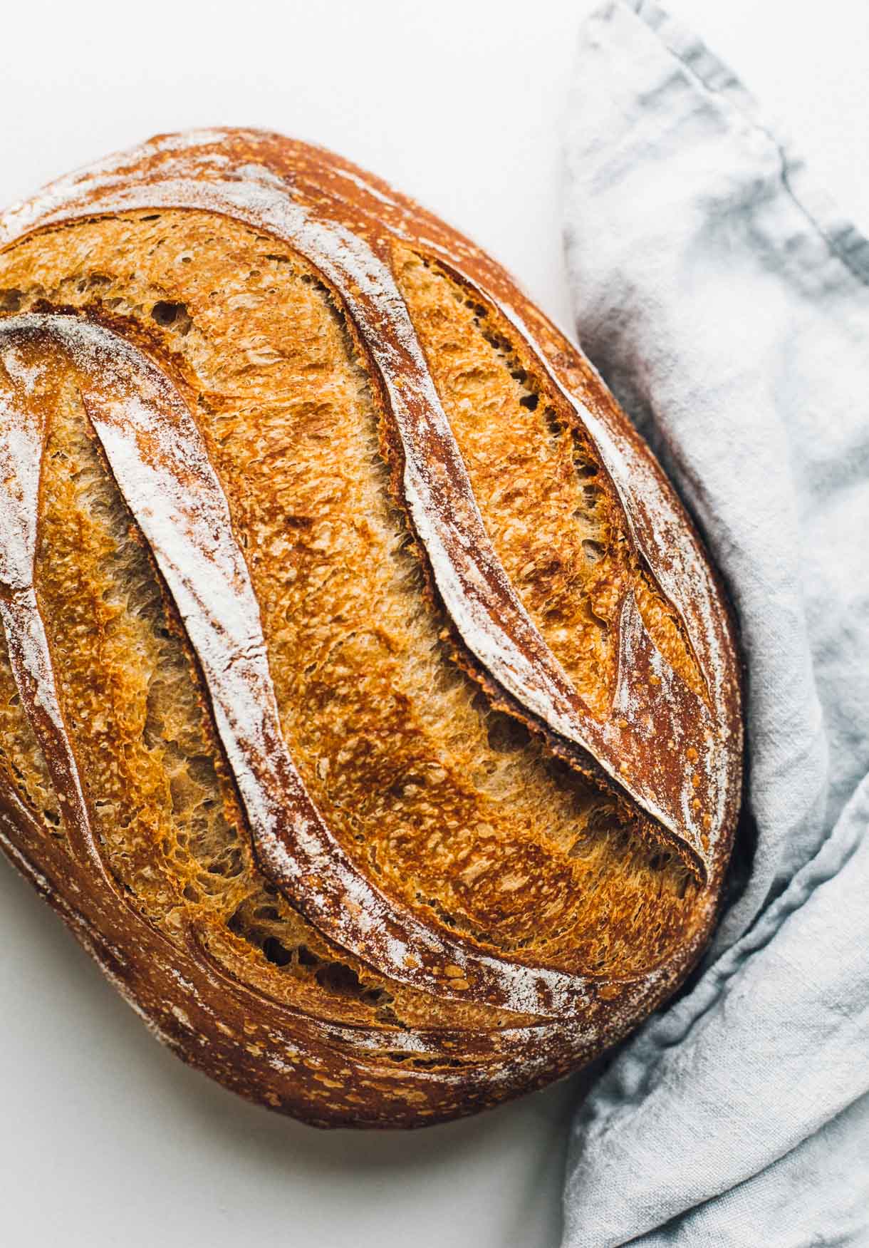 loaf of spelt sourdough bread with blue linen.