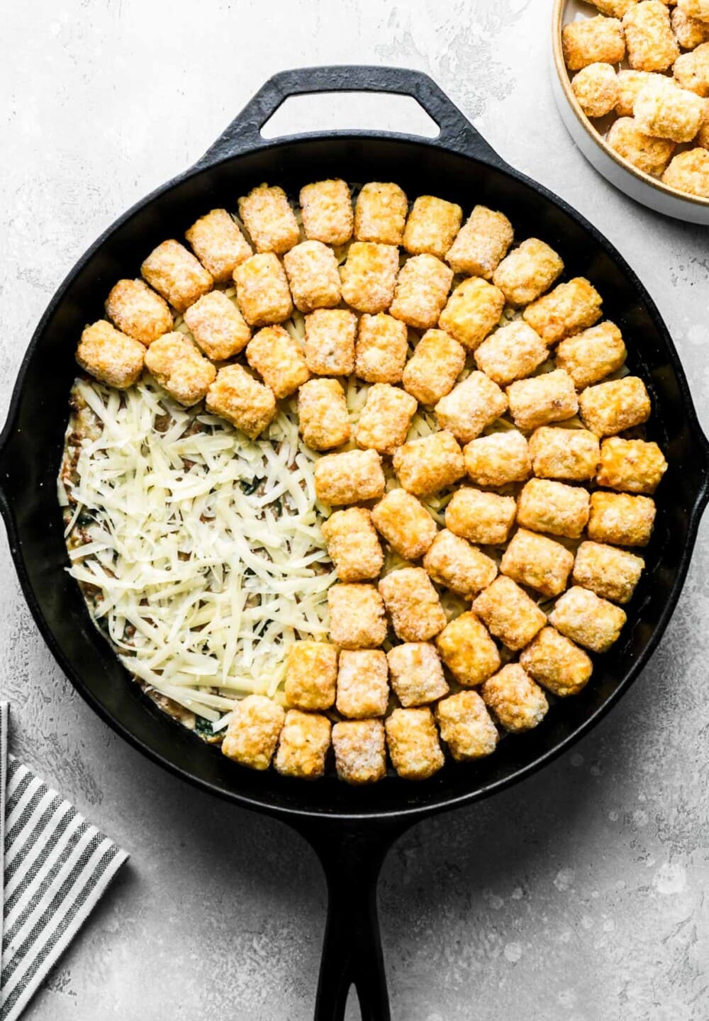 tater tot hotdish, prepared in a cast iron skillet, uncooked.