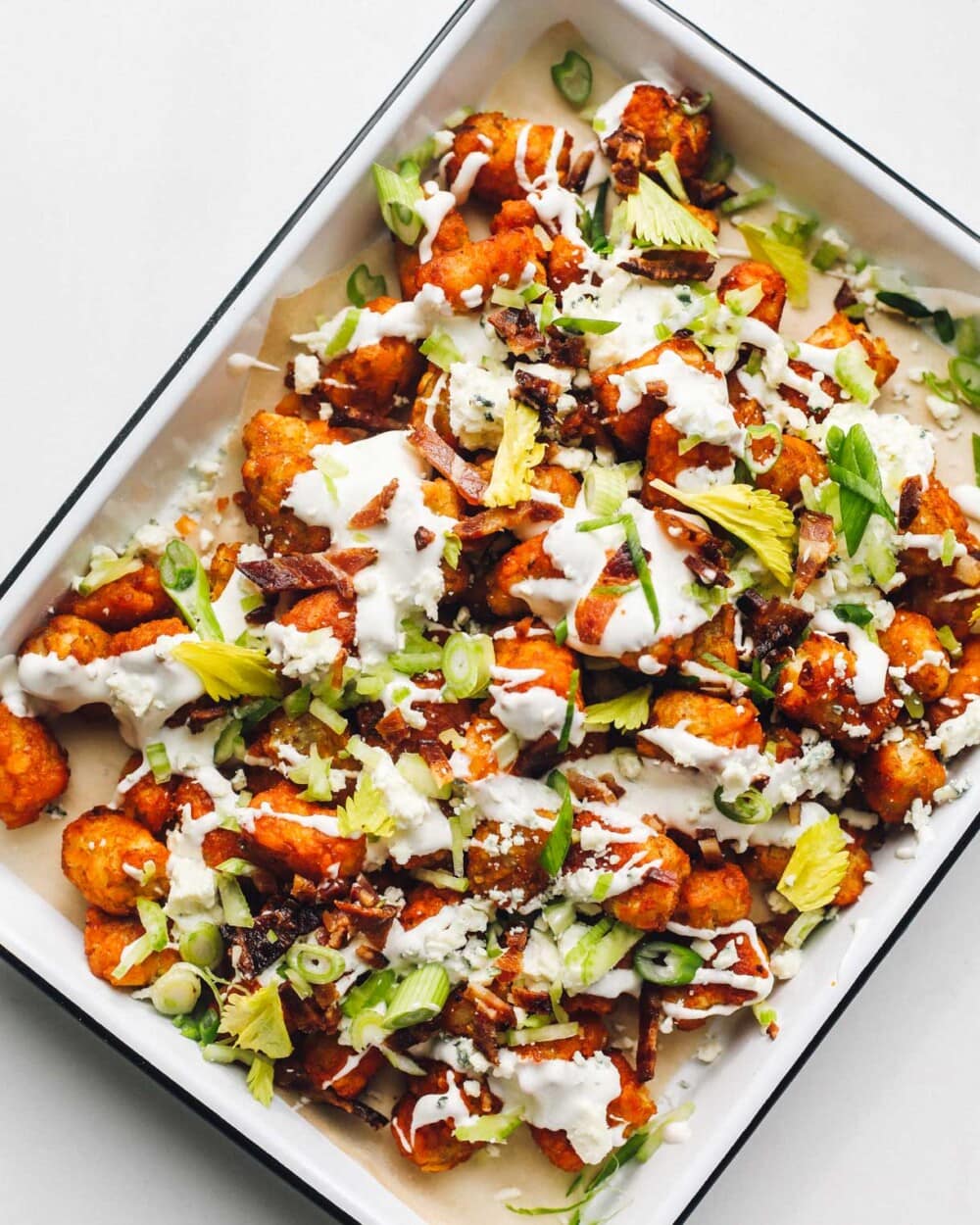 loaded buffalo tater tots in a white enamel pan.