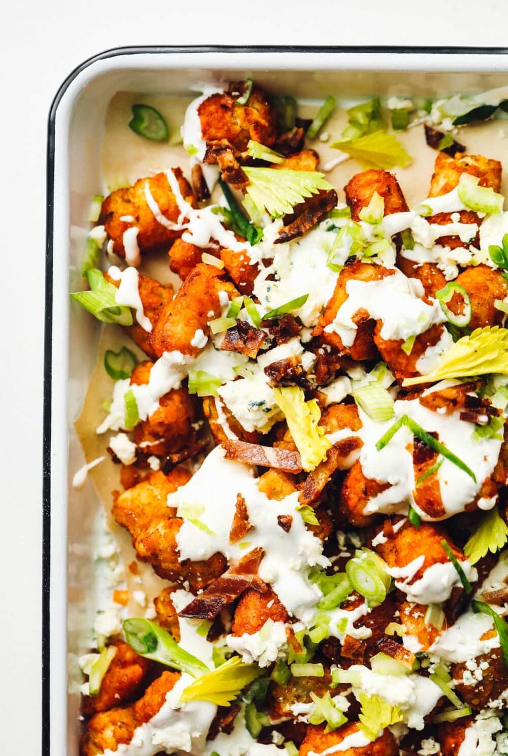 loaded buffalo sauce tater tots in a white pan