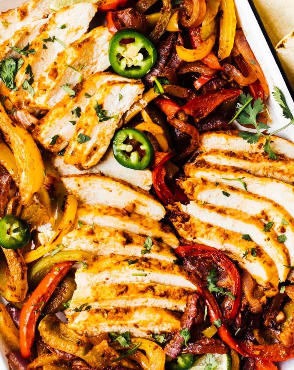 sliced chicken fajitas and peppers in a pan