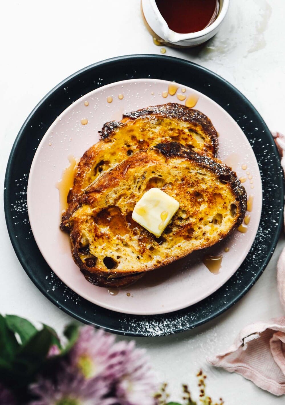 french toast on pink plate with maple syrup and butter