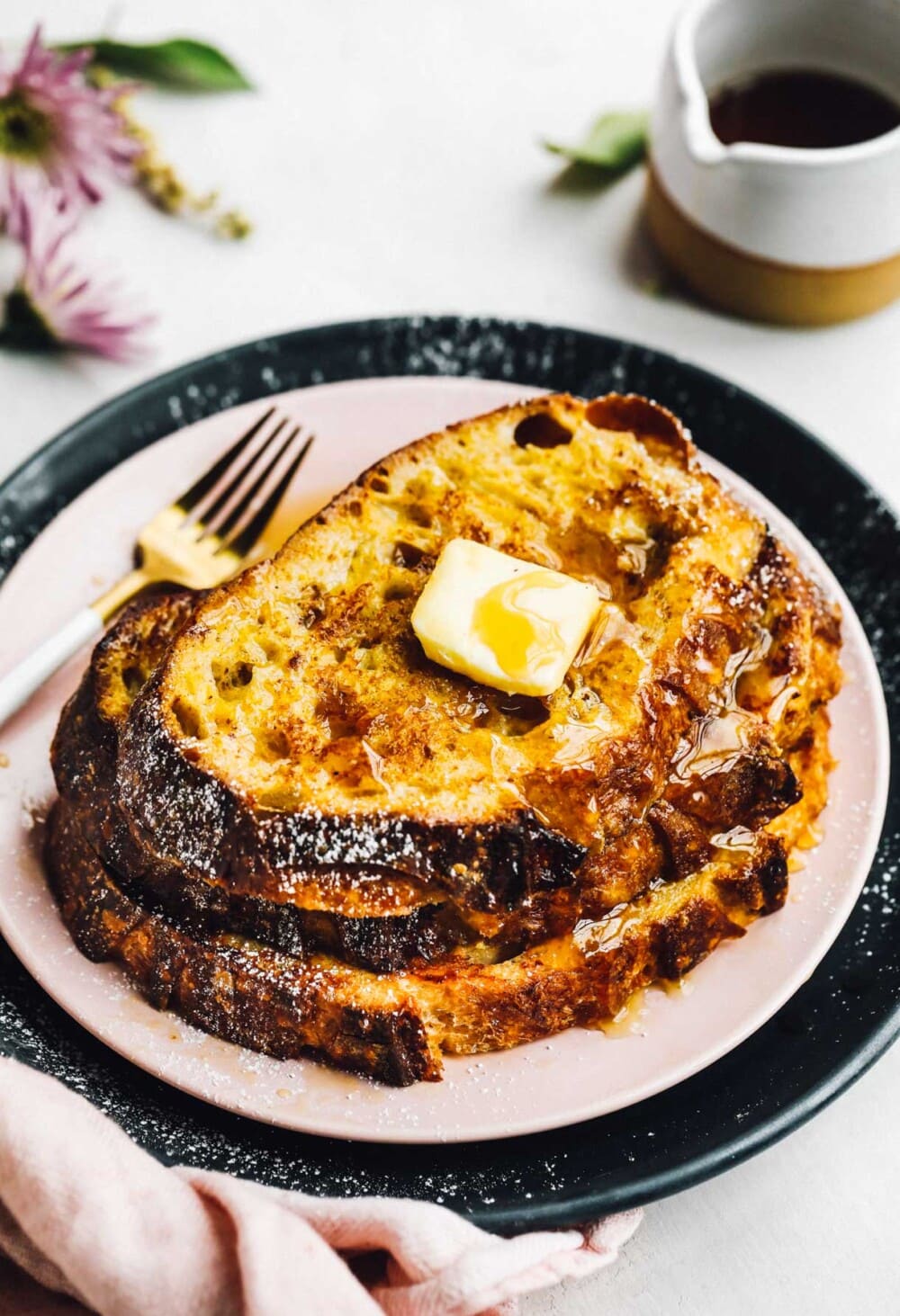 french toast stacked on pink plate with gold fork