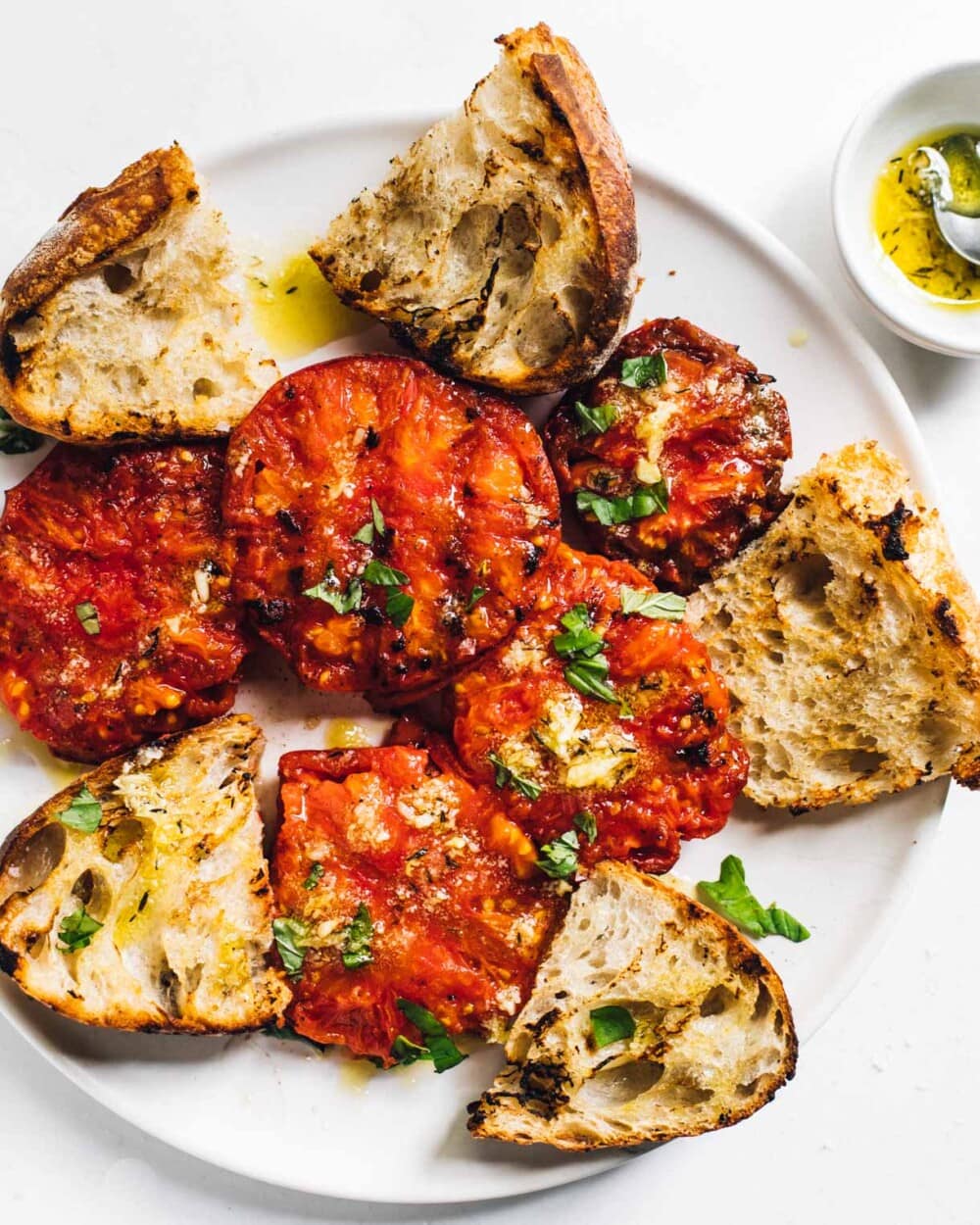 grilled tomatoes on a white plate with grilled bread