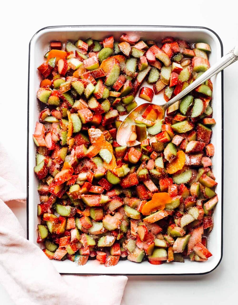 cut rhubarb pieces in a white tray with silver spoon