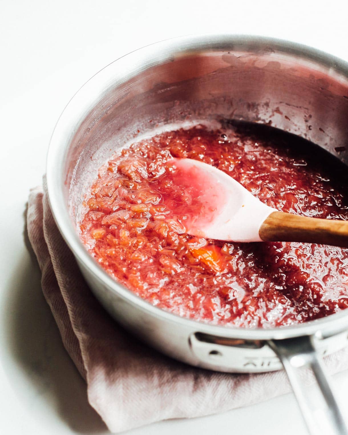 rhubarb sauce in a steel pot with a pink spoon