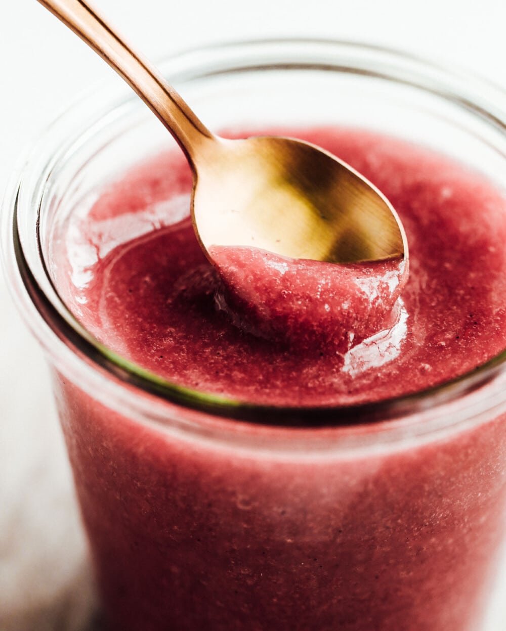 rhubarb sauce in glass jar with gold spoon