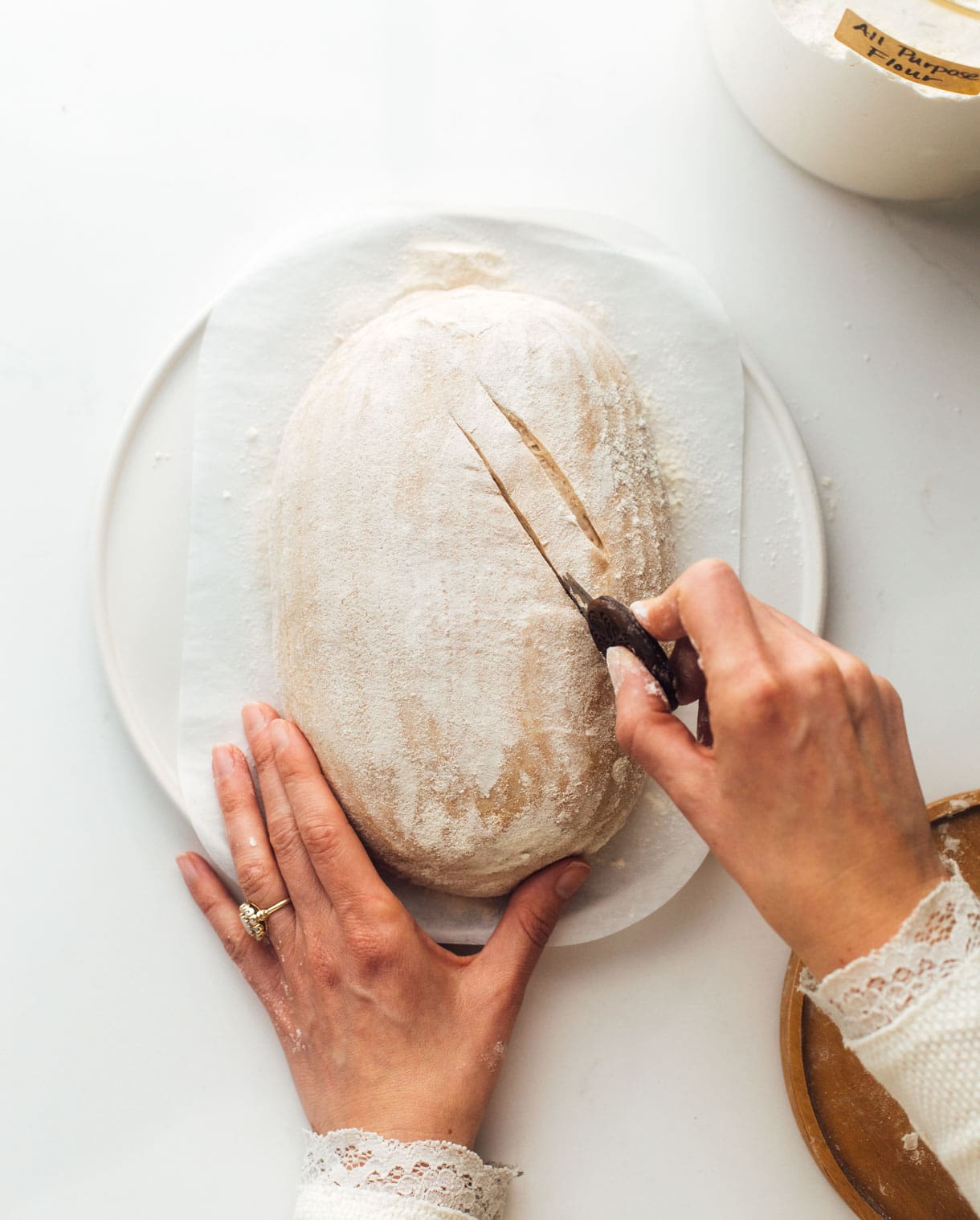 woman scoring sourdough bread with bread lame 