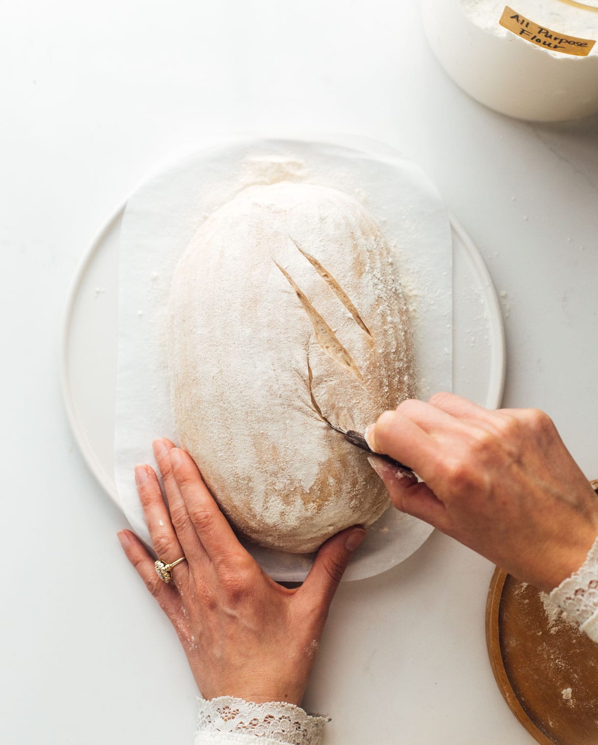 woman scoring sourdough bread with bread lame 