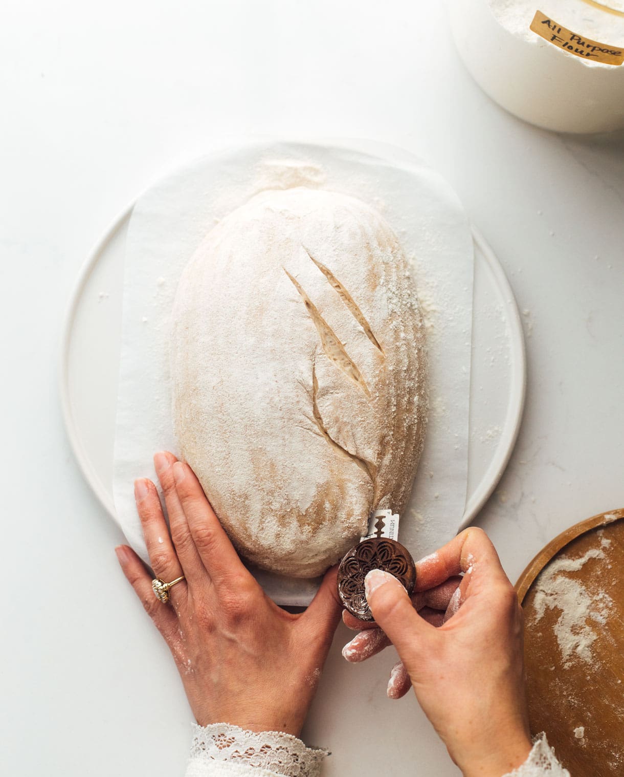 woman scoring sourdough bread with bread lame 