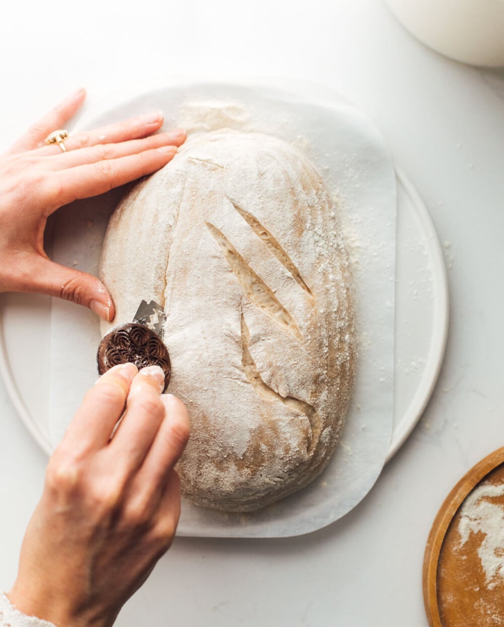 woman scoring sourdough bread with bread lame