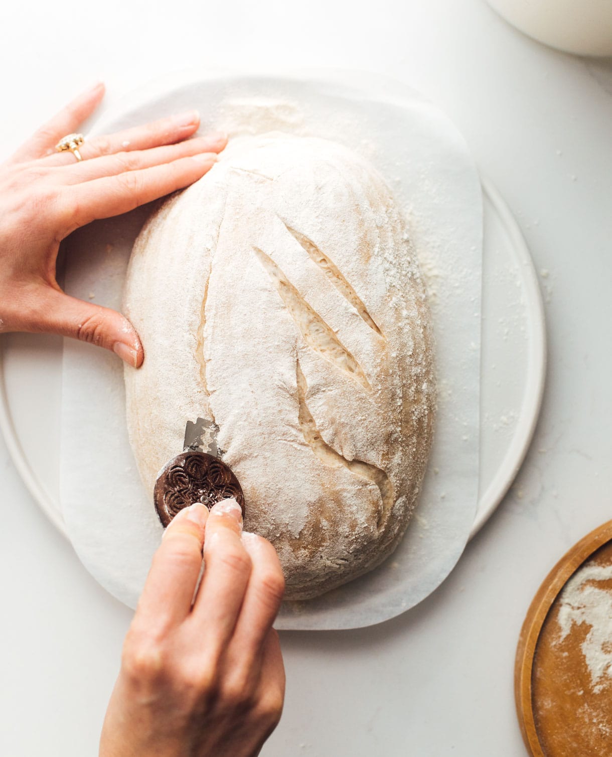 woman scoring sourdough bread with bread lame 