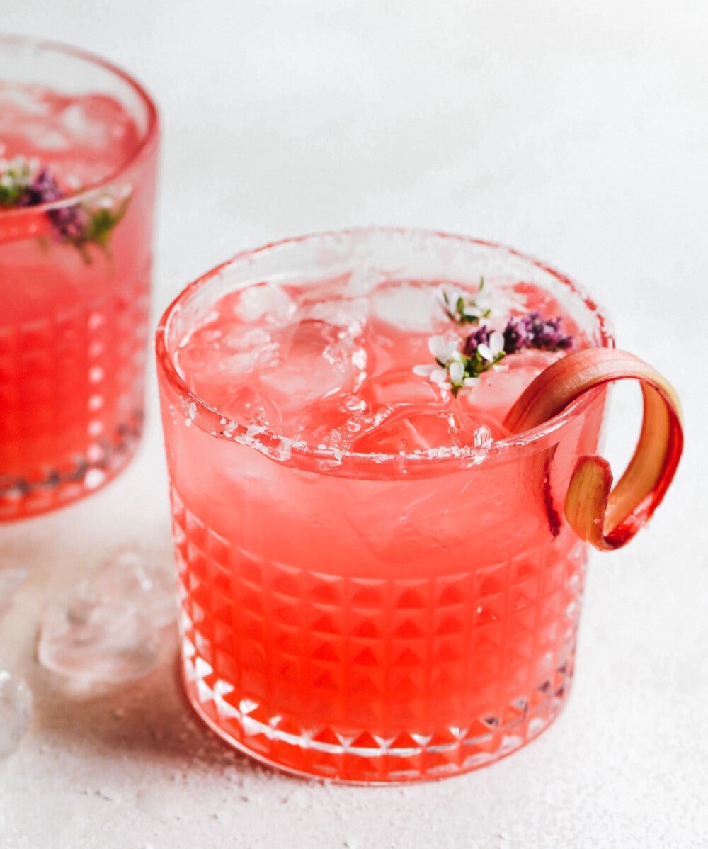 rhubarb margarita in clear glass with salt on the rim