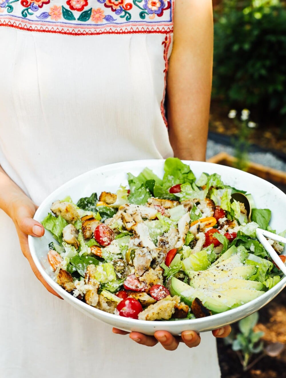 woman holding chicken caesar salad