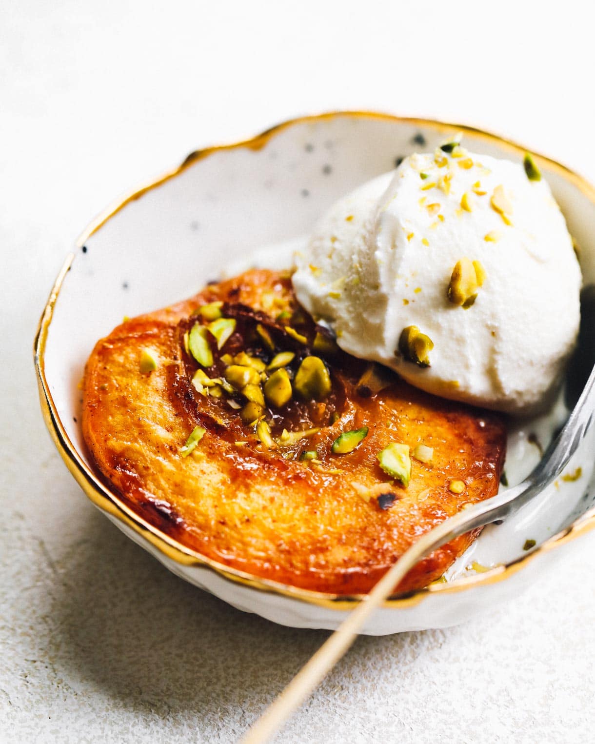 baked peaches with ice cream and crushed pistachios