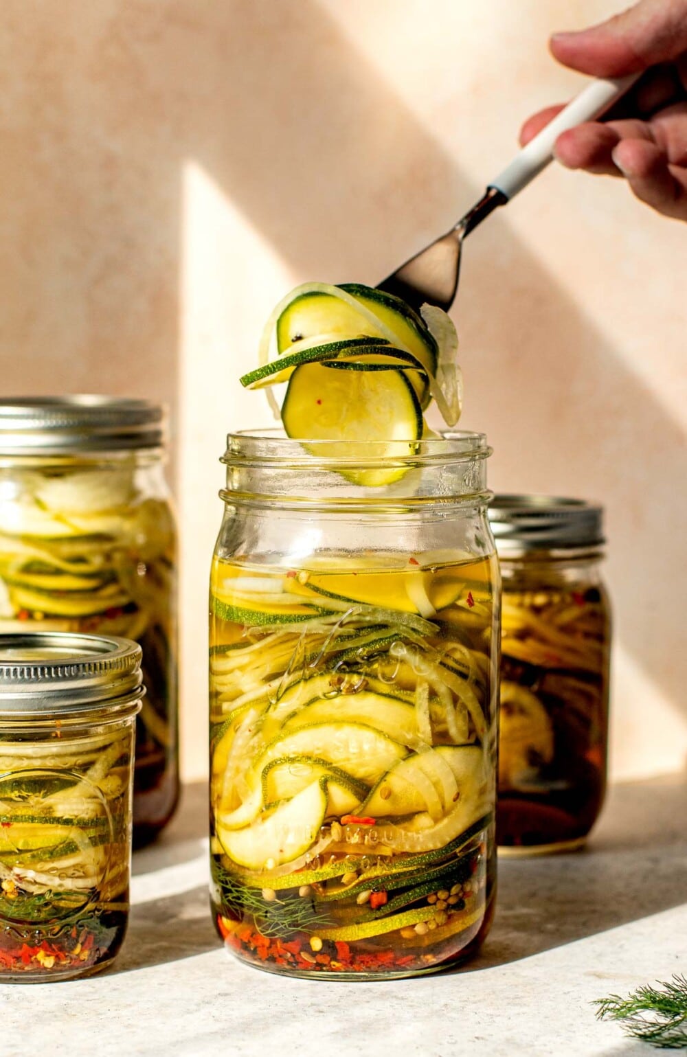grabbing zucchini pickles out of a glass jar with a fork
