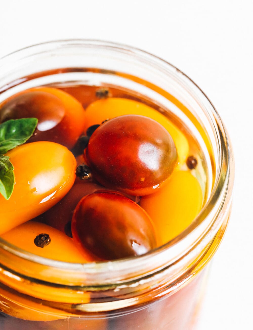 pickled cherry tomatoes with basil in a glass jar