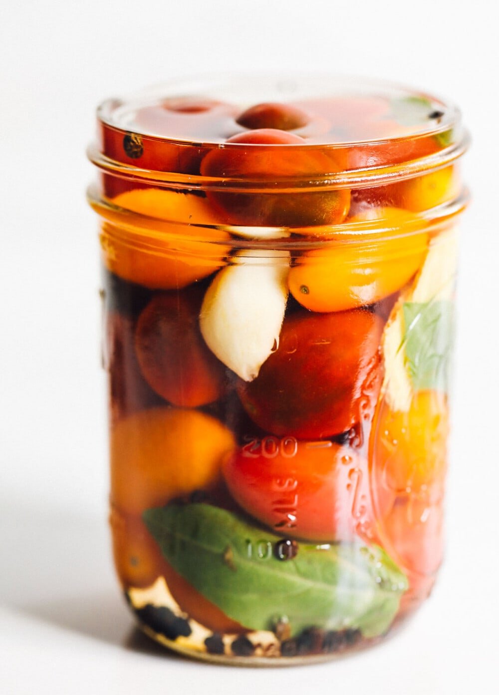 pickled cherry tomatoes with garlic and basil in a glass jar