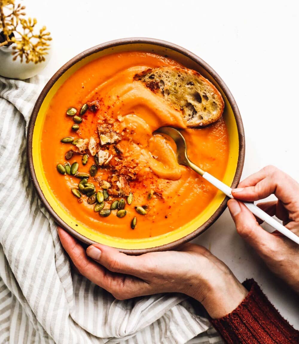 buttercup squash soup in yellow bowl with woman holding the bowl.