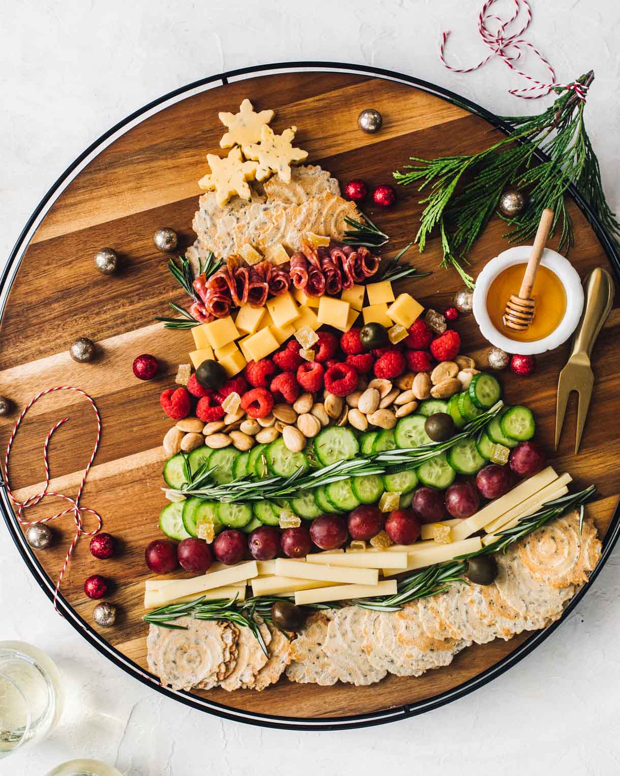 christmas tree charcuterie board on wooden cheese board with honey alongside.